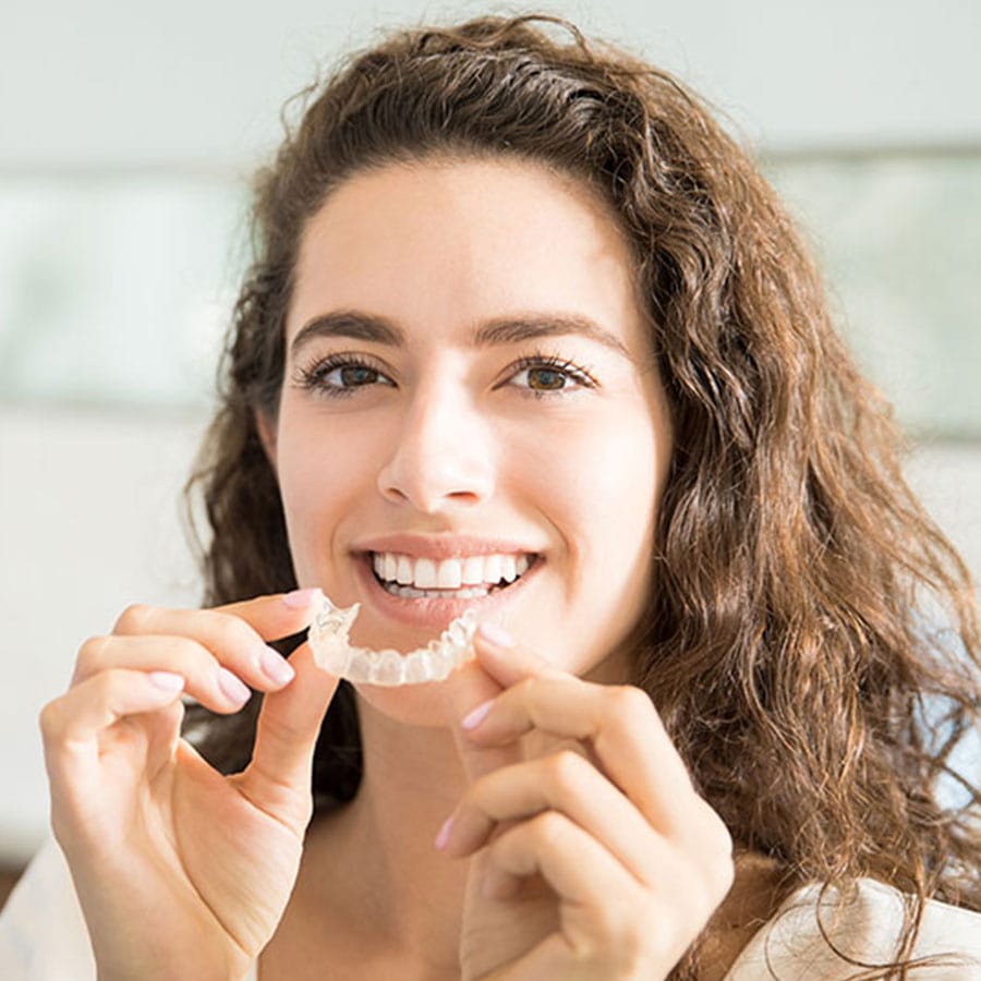 young woman placing Invisalign clear braces in her mouth