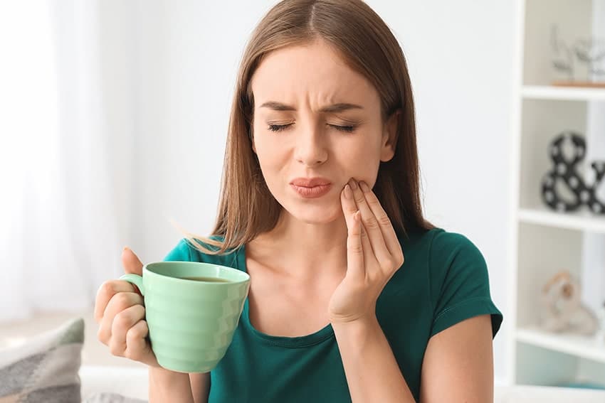 Young woman has pain after drinking coffee
