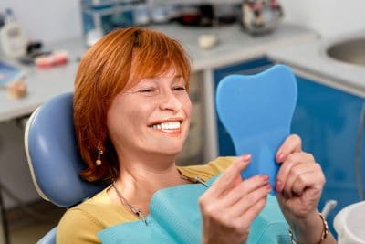 happy red haired woman shows off her smile at the dentists office