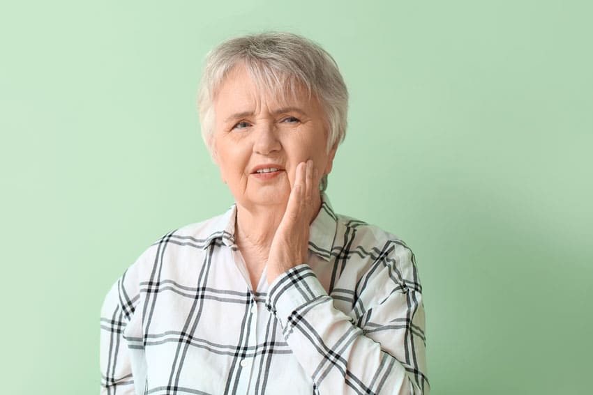 senior adult woman holding her jaw in pain